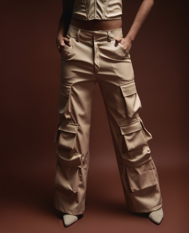 High-waisted beige cargo pants with multiple pockets, styled for a modern fashion look. Perfect for streetwear and casual outfits, showcasing trendy and versatile clothing by Shacra.