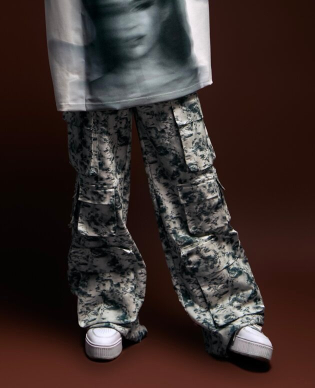 Cargo pants with a black and white camouflage pattern and chunky white sneakers, styled for a streetwear look.