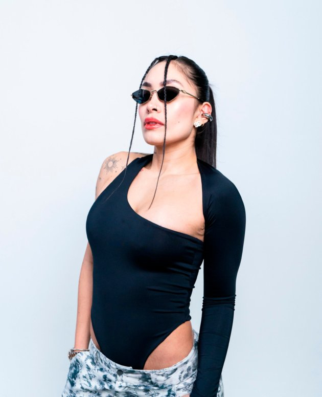 Chic woman wearing stylish sunglasses, black bodysuit, and trendy tie-dye pants, showcasing modern fashion and confident attitude. Perfect for fashion-forward looks and urban style inspiration.
