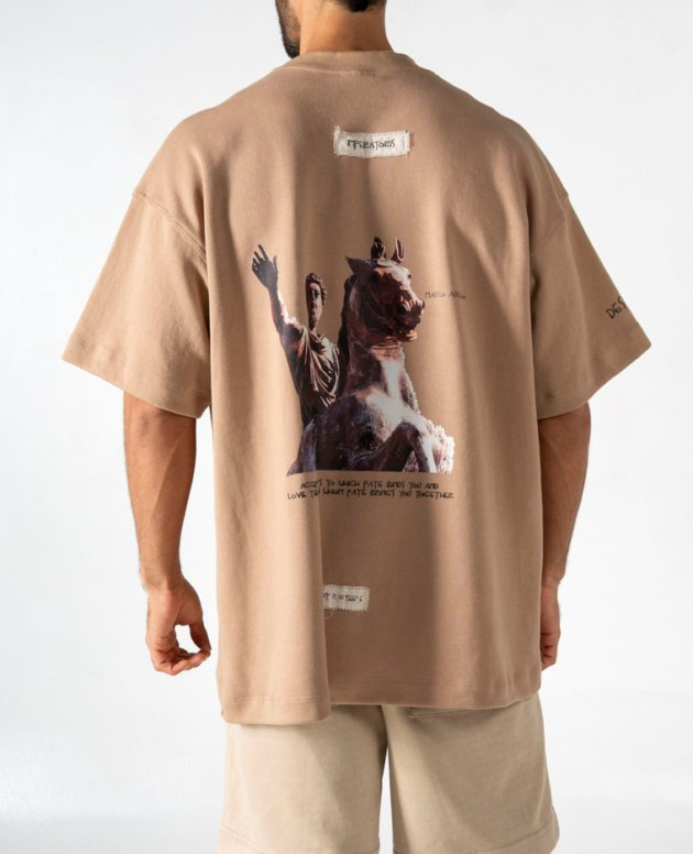 Men's oversized beige graphic t-shirt with artwork and text, casual streetwear fashion.