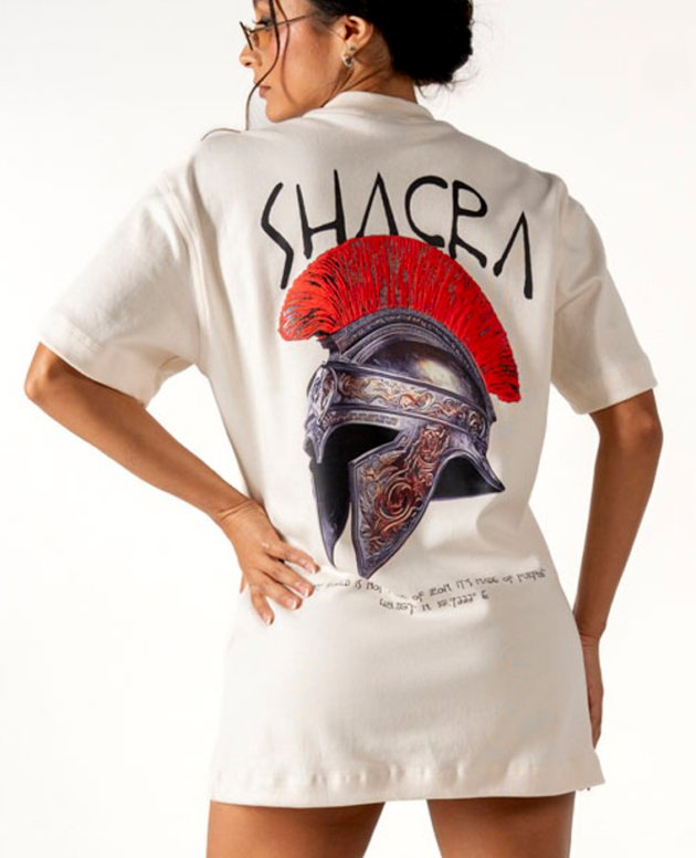 Bold graphic T-shirt featuring a detailed ancient Greek helmet with red plume, stylishly worn by a woman showcasing modern fashion and artistic design elements, perfect for trendy streetwear.
